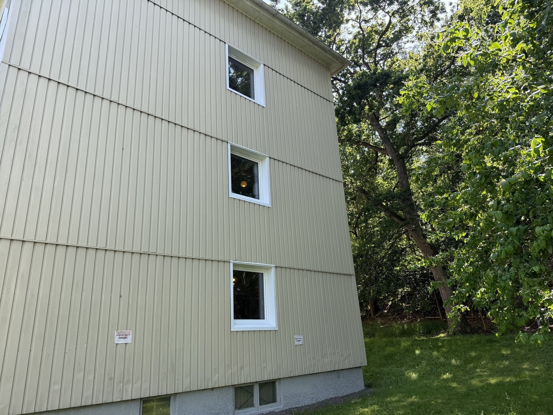 Gavel på flerbostadshus med nyinstallerade vita fönster och vertikal träpanel