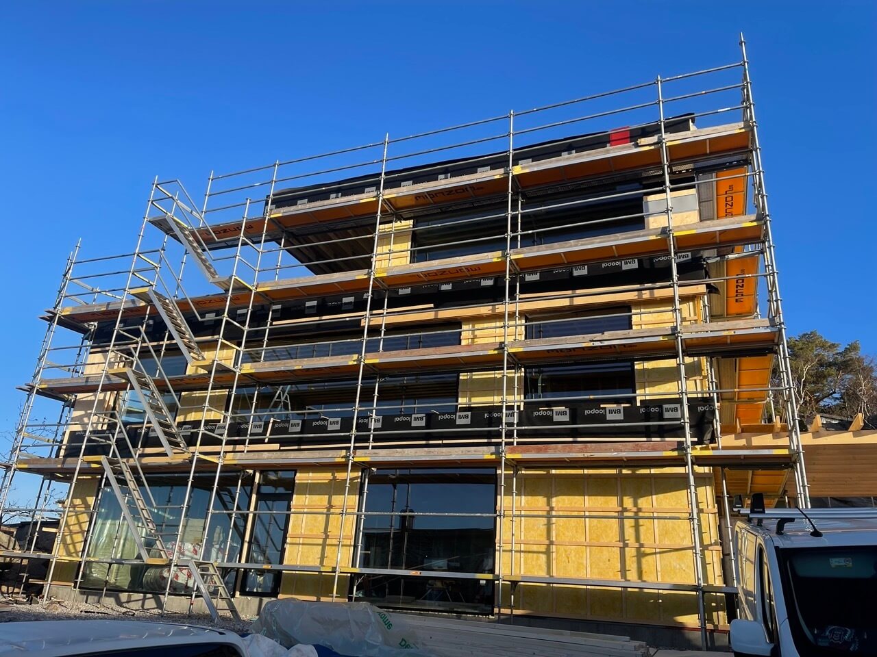 Flerbostadshus under nybyggnation med ställning och nyinstallerade fönster