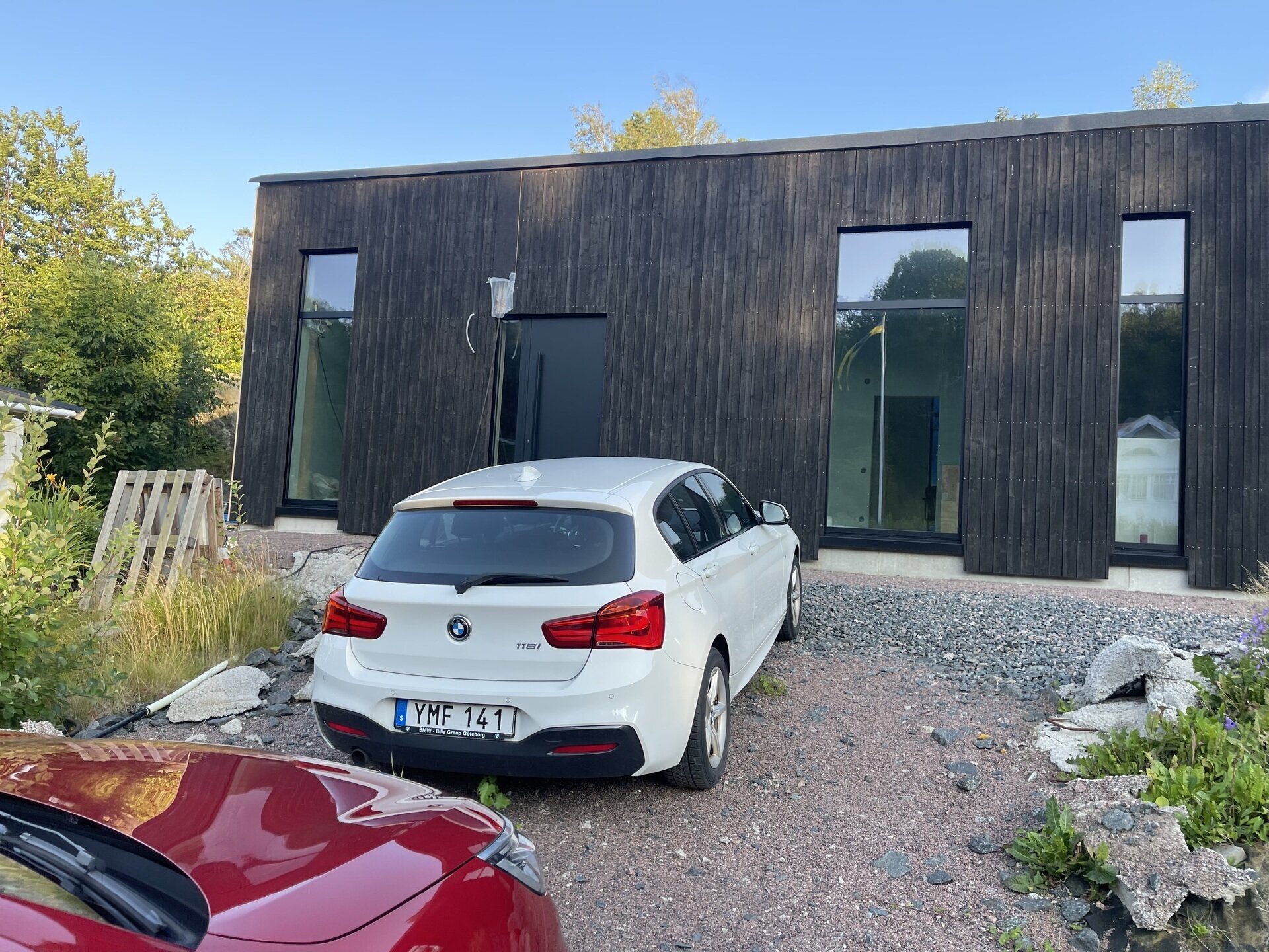 Färdig mörk träpanelbyggnad med stora svarta fönsterpartier sedd utifrån