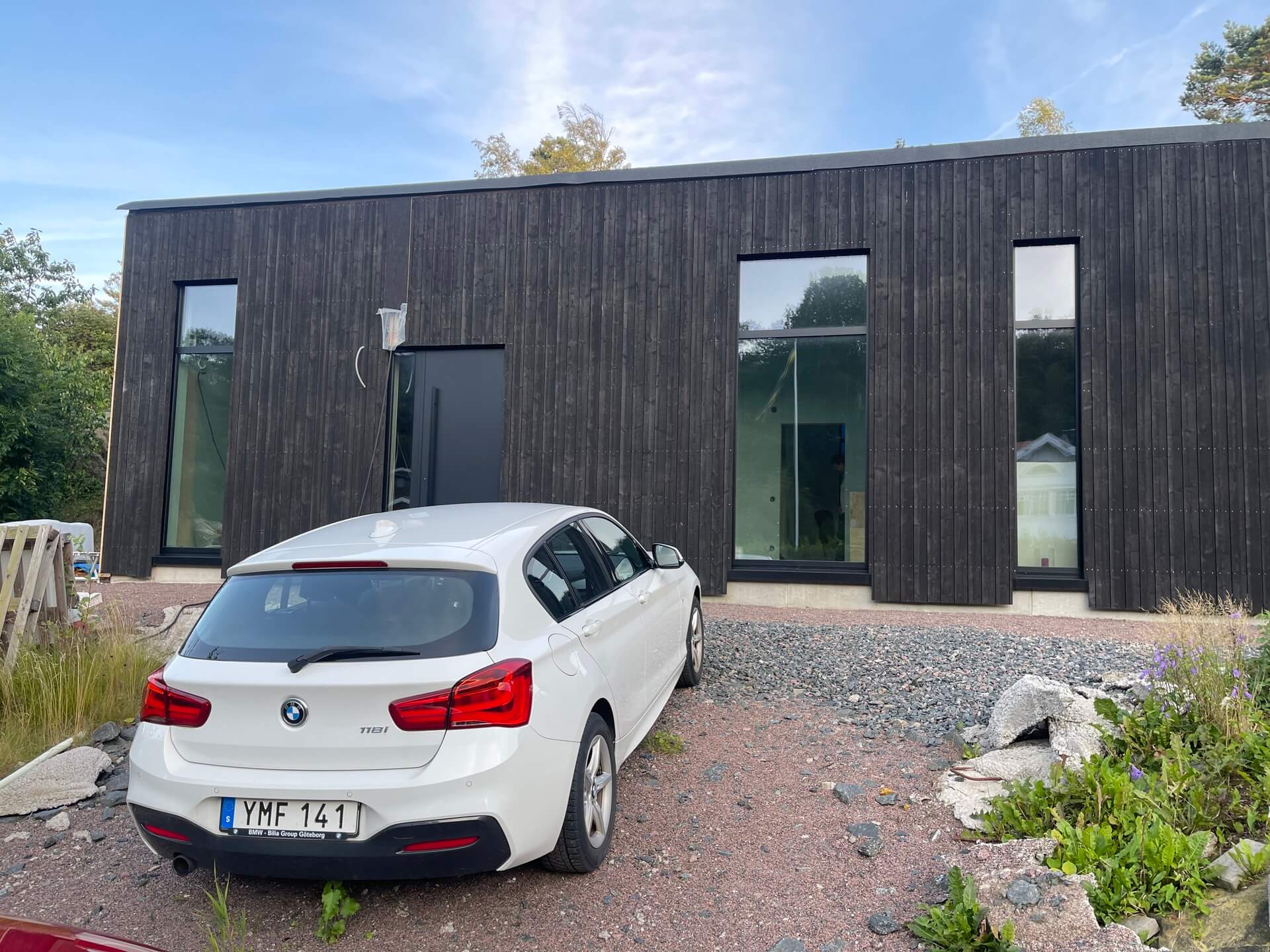 Färdig mörk träpanelbyggnad med asymmetriskt placerade svarta fönsterpartier