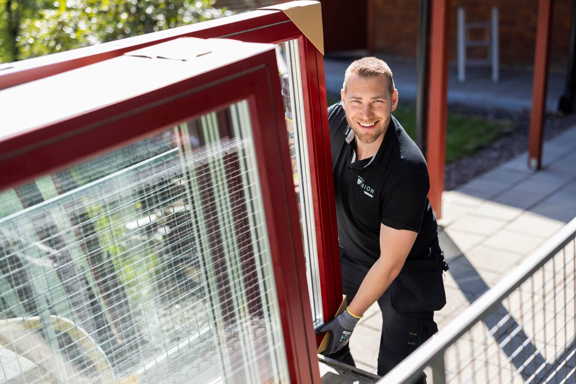 Montör från Vision Entreprenad bär ut gammalt fönster med leende