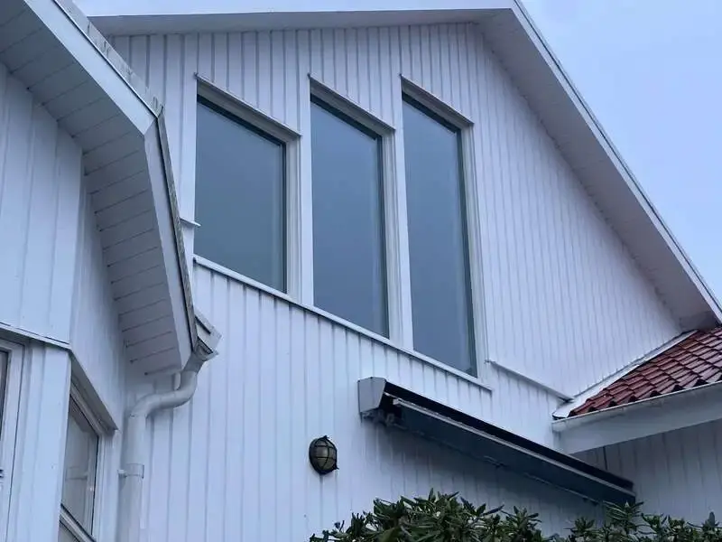 Närbild på tre nyinstallerade fönster i gavelspets på vit träpanelfasad – utfört av Vision Entreprenad