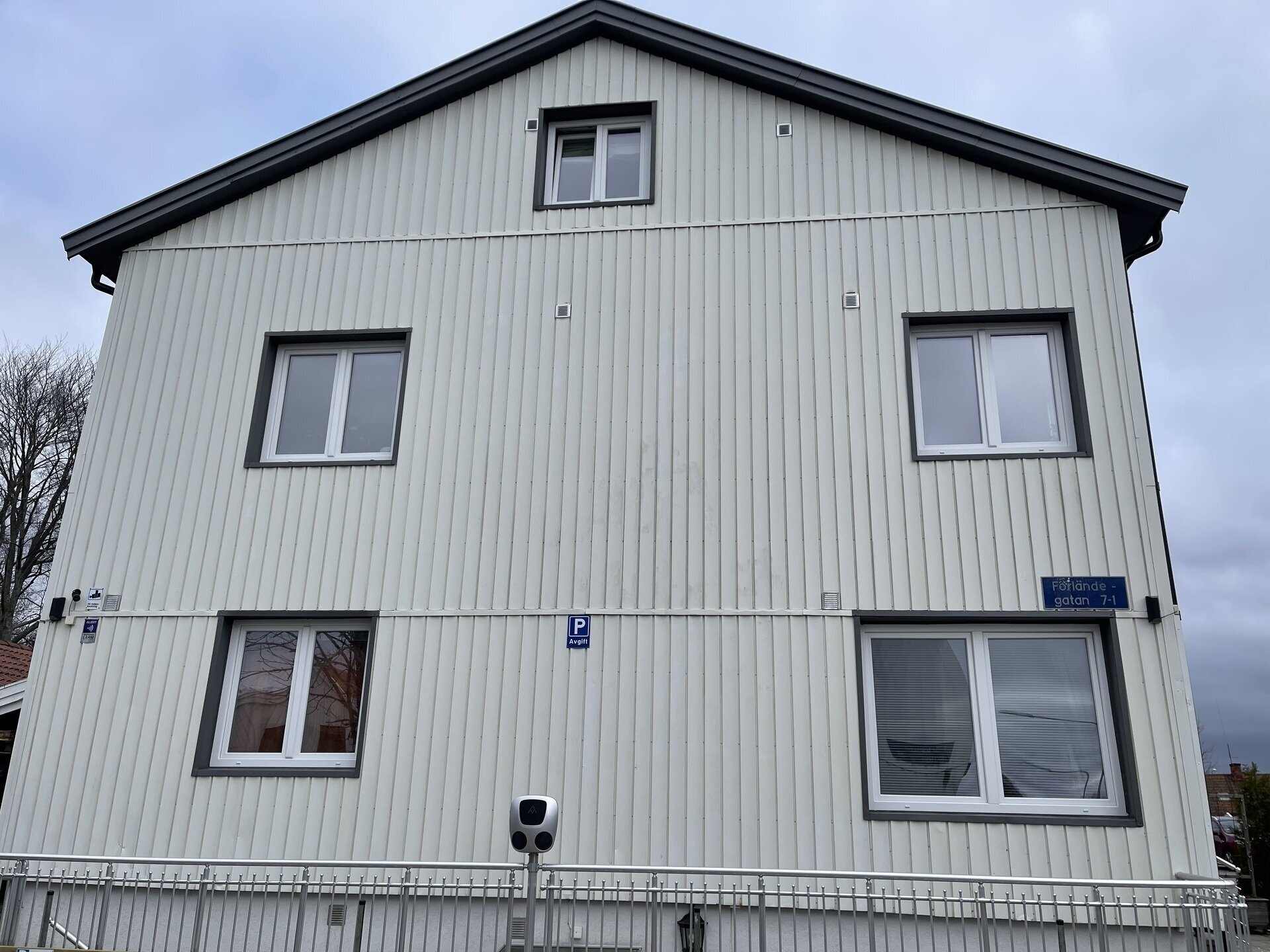 Vit flerfamiljsfastighet med nyinstallerade fönster med mörka karmar