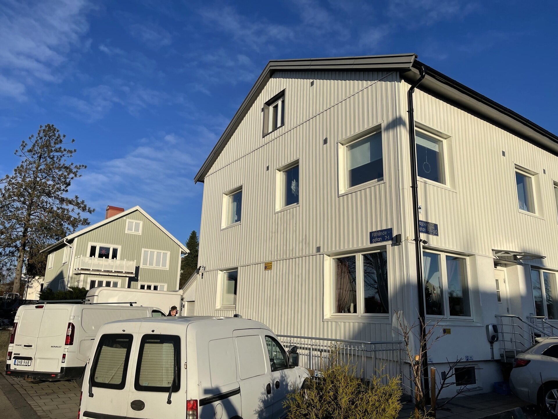 Vit flerfamiljsfastighet med nyinstallerade fönster och servicebil uppställd