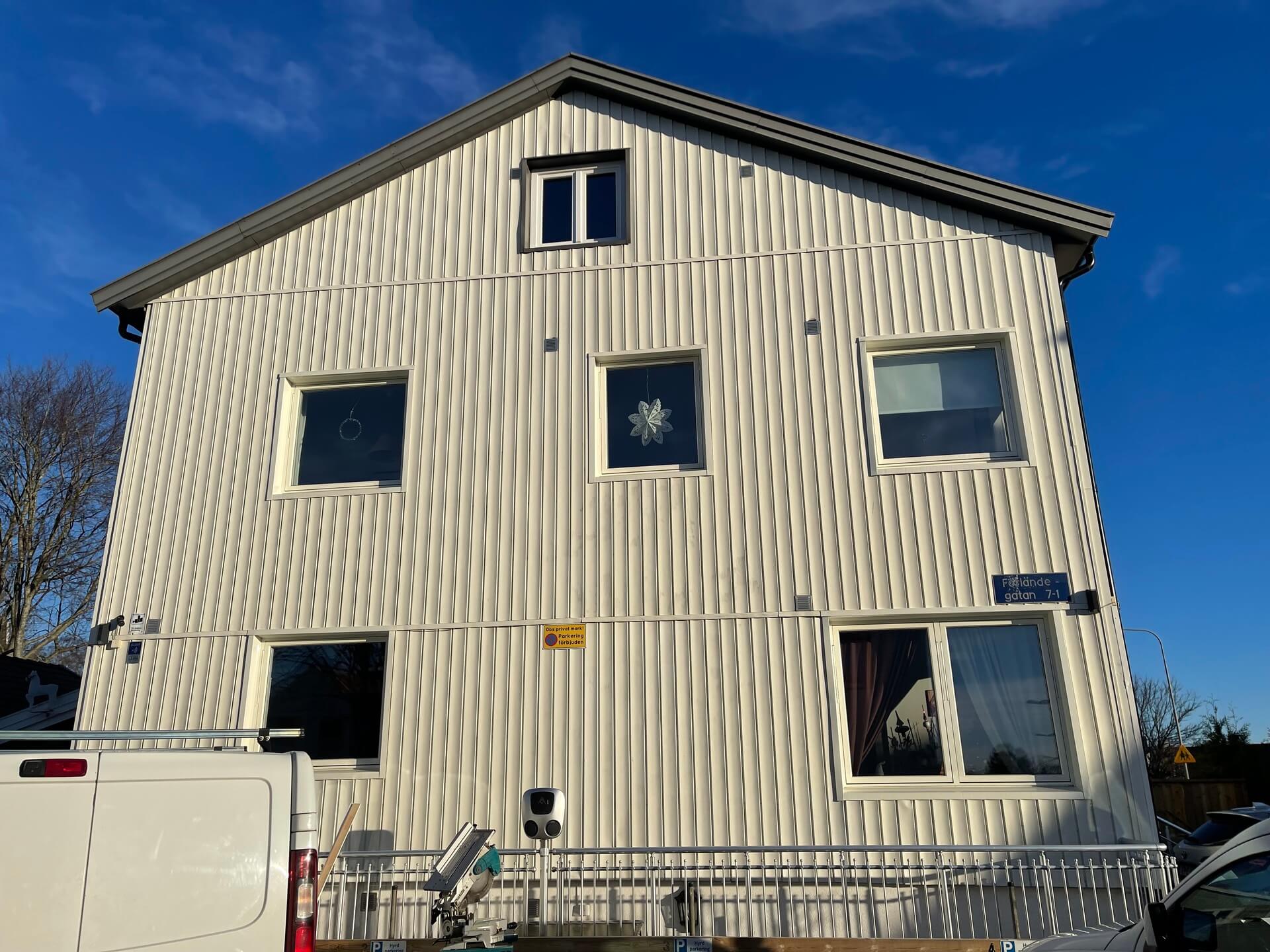Baksida av vit flerfamiljsfastighet med nyinstallerade fönster i solsken