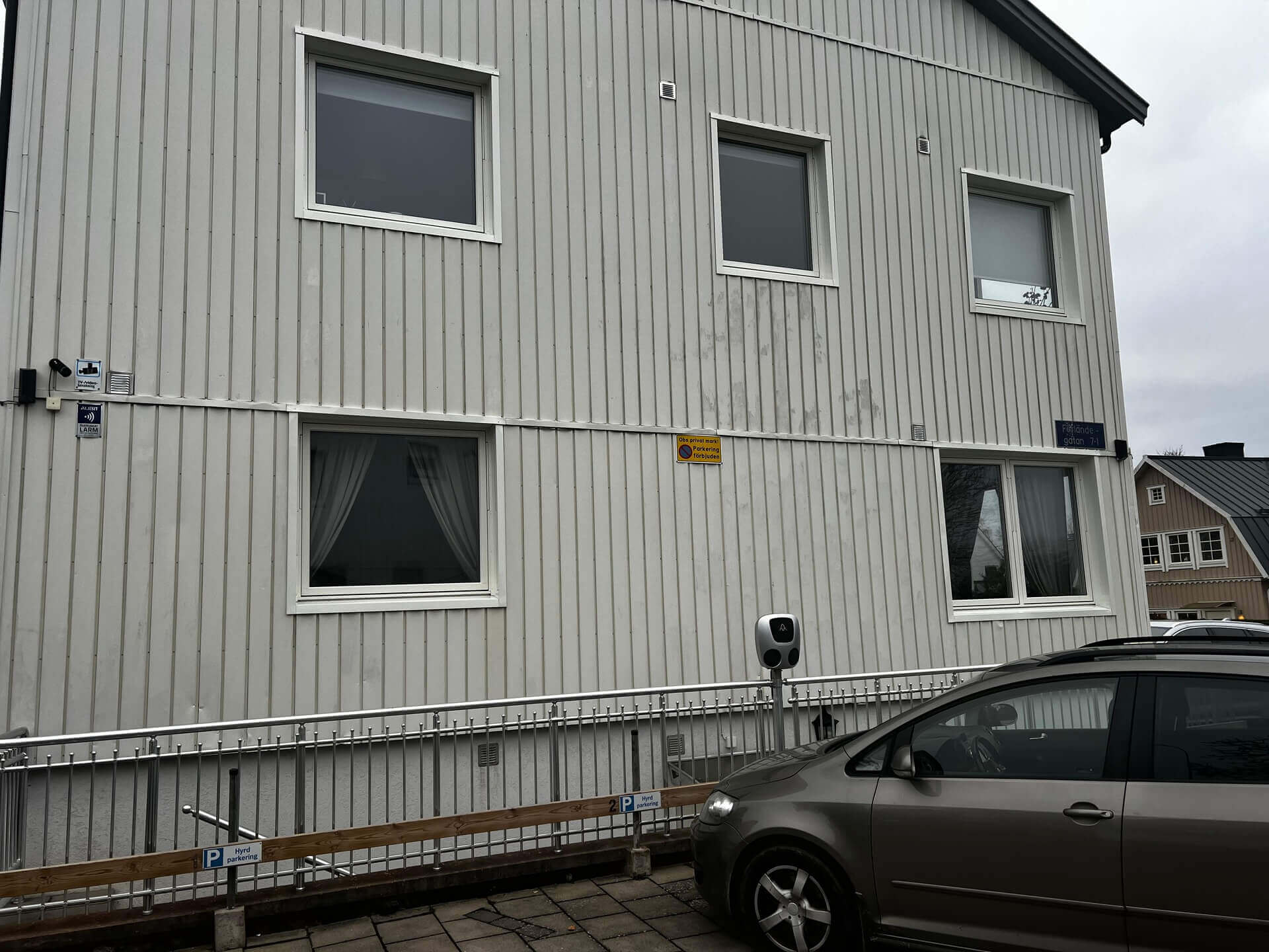 Närbild på vit vertikal träpanelfasad med nyinstallerade fönster med vita karmar