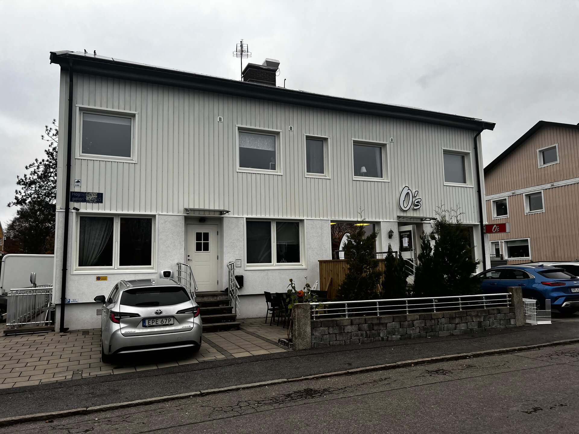 Vit flerfamiljsfastighet med nyinstallerade vita fönster och mörka karmar sedd från gatan
