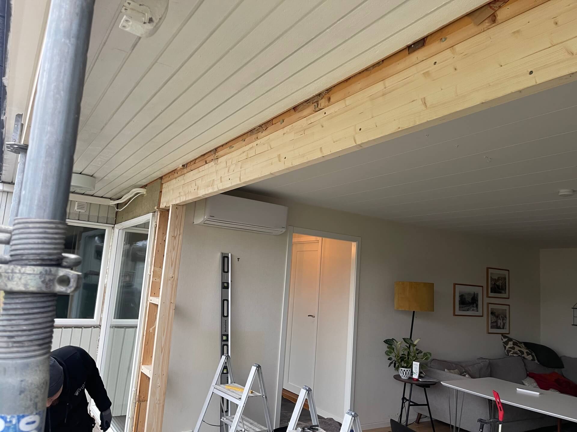 Närbild på ny träavväxling ovanför dörröppning under pågående fönsterbyte