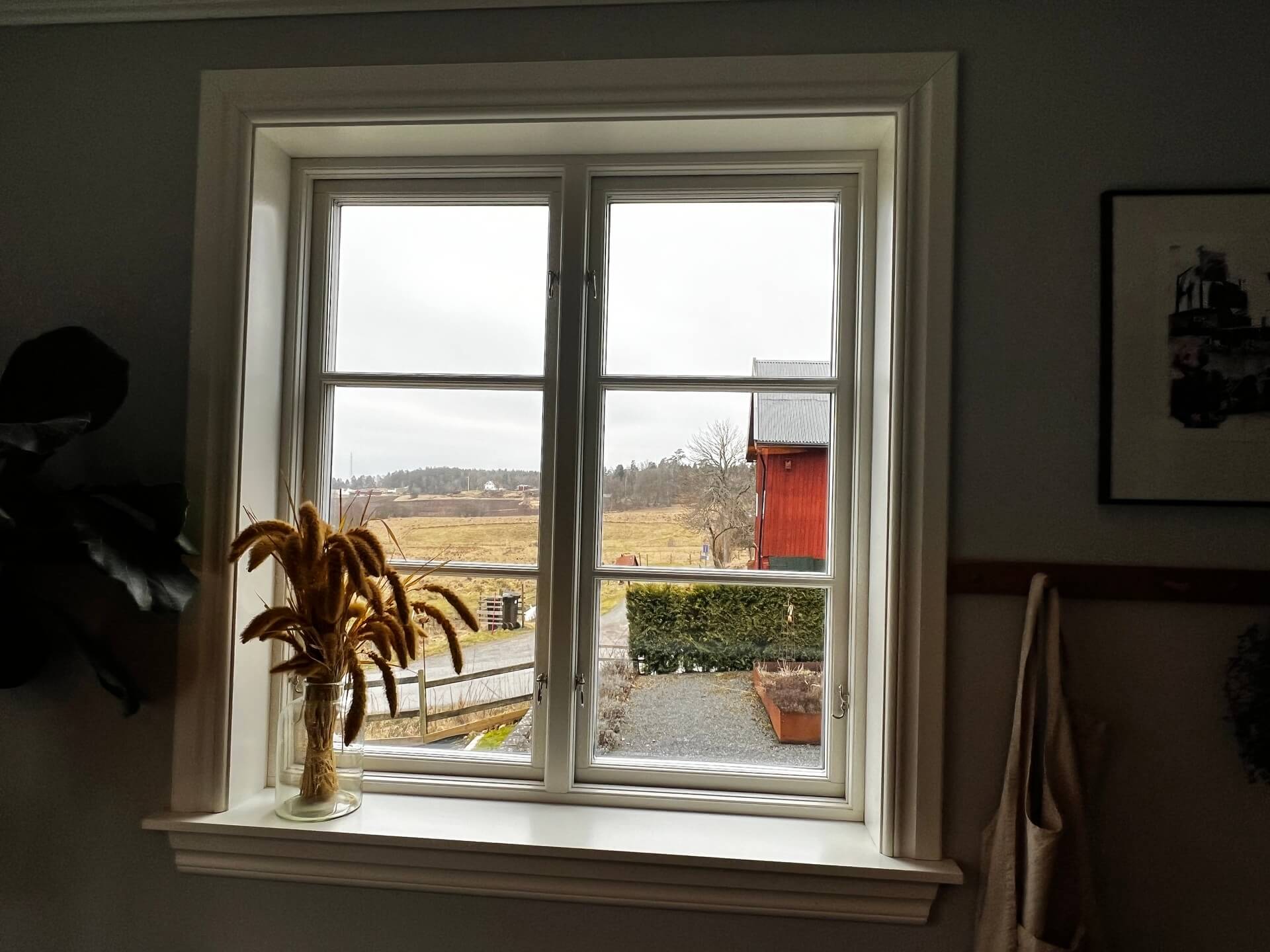 Nyinstallerat tvåluftsfönster med vit karm och utsikt över landsbygd i matrum