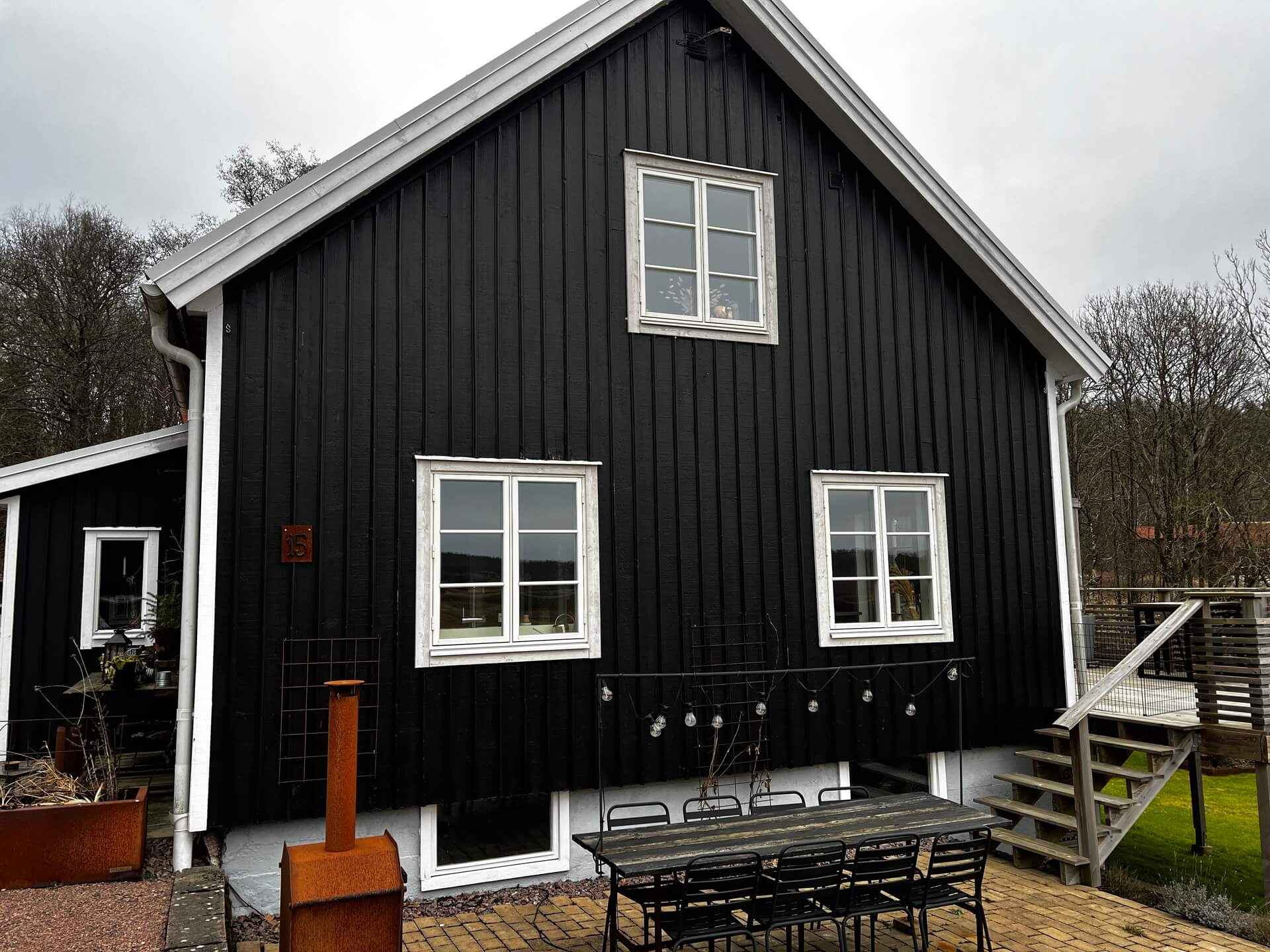 Mörk villa med svart träpanelfasad och nyinstallerade vita fönster