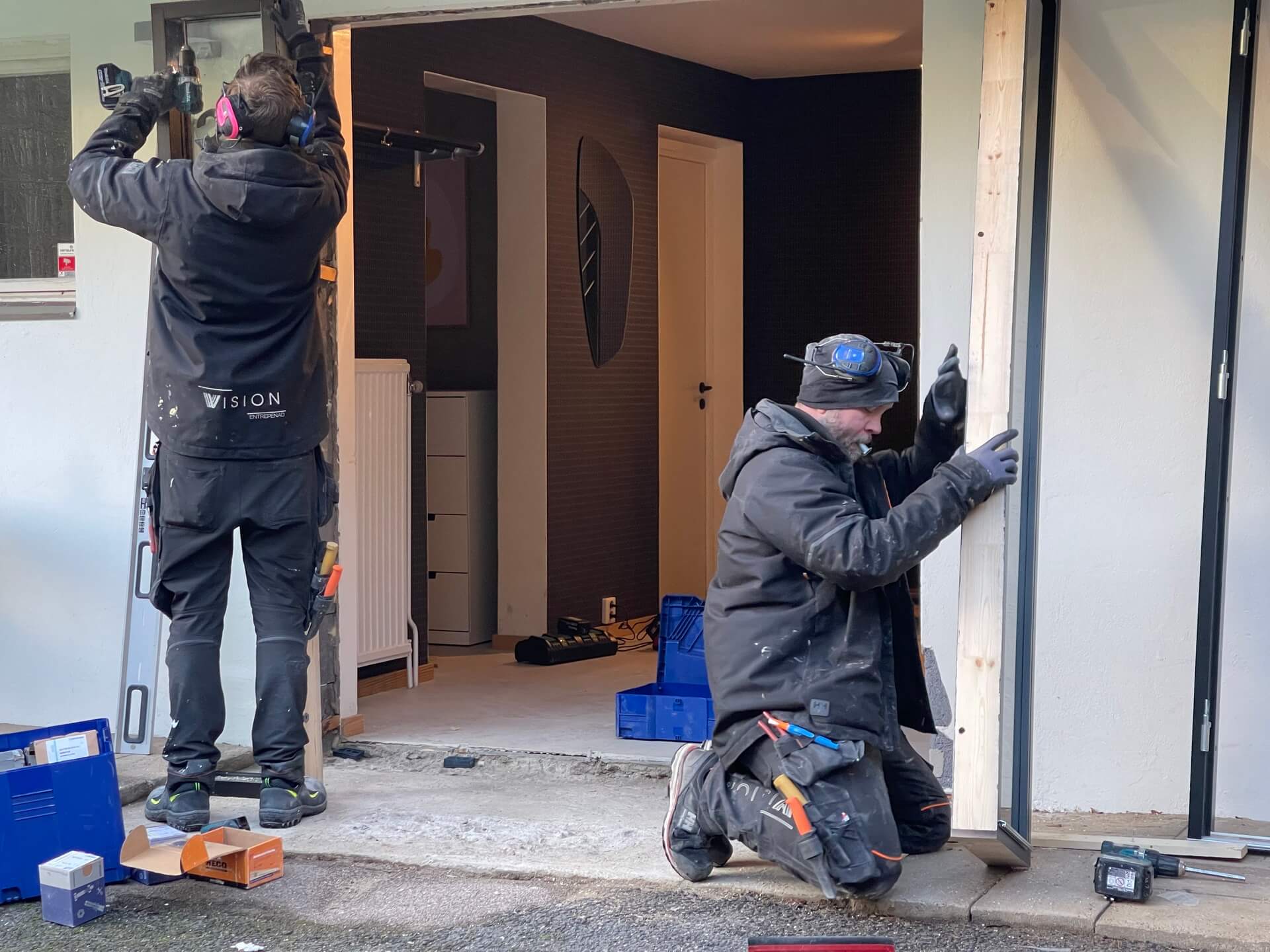 Montörer från Vision Entreprenad justerar och skruvar fast ny ytterdörrkarm