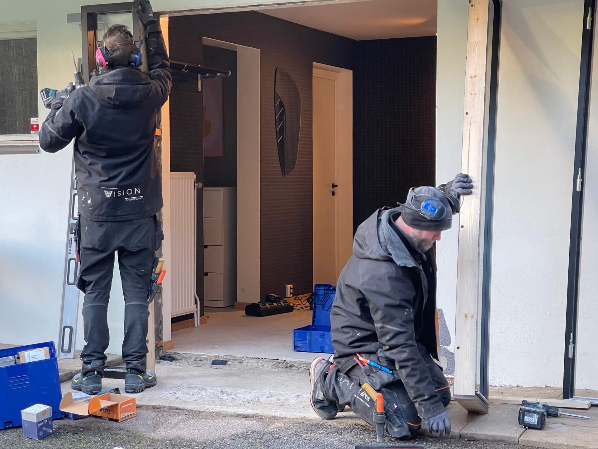 Två montörer från Vision Entreprenad monterar ny ytterdörrkarm i putsad fasad