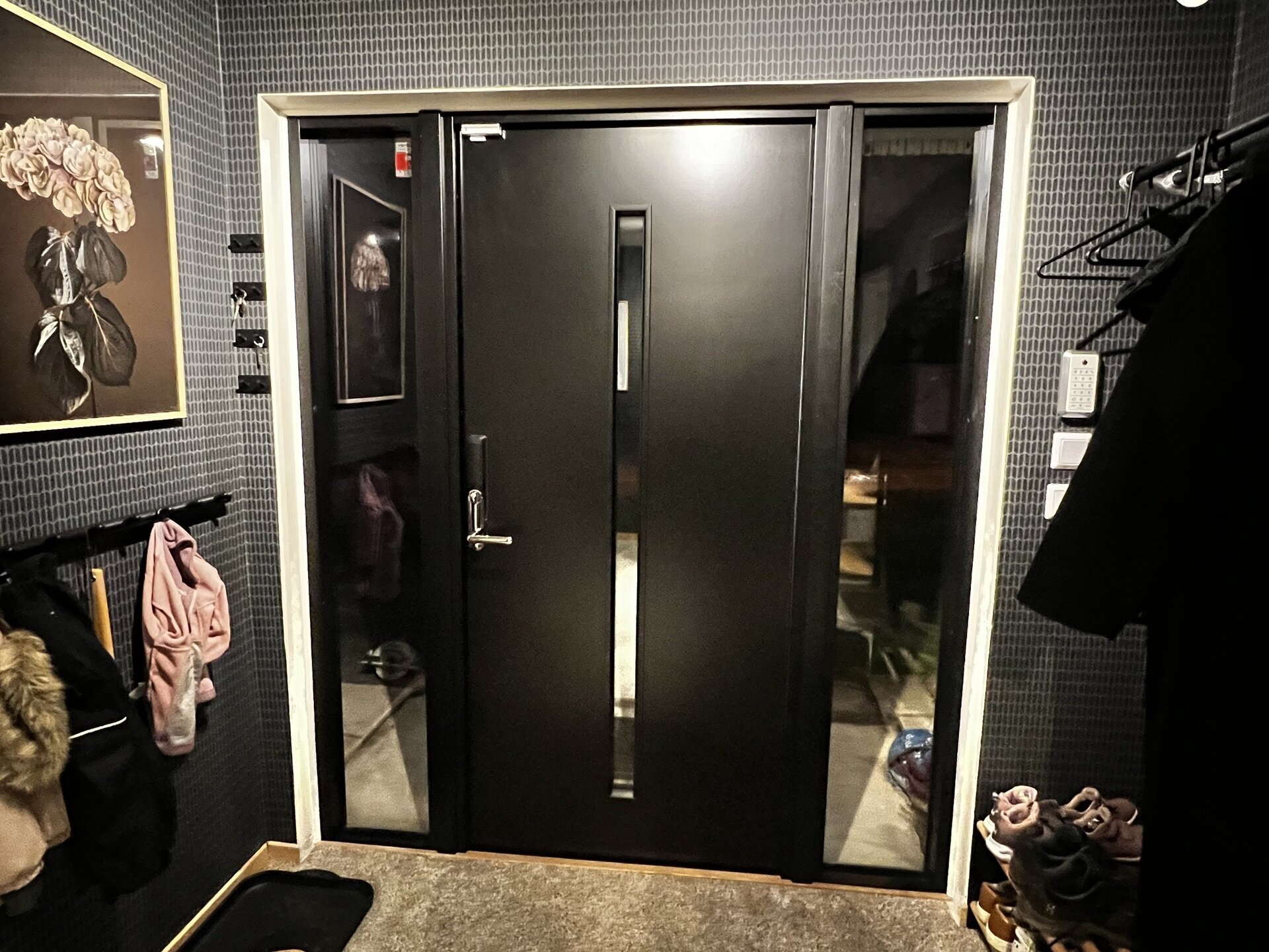 Nyinstallerad svart ytterdörr med smalt sidoljus sedd inifrån hall