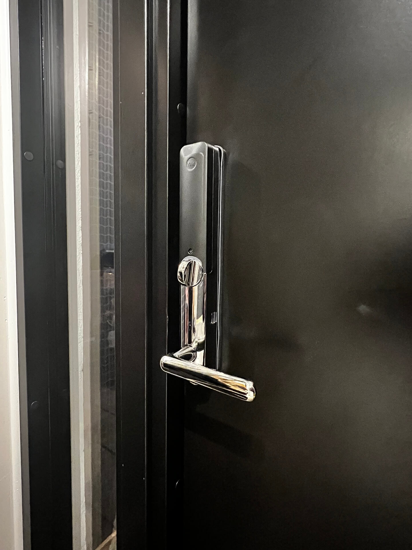 Närbild på handtag och låsdetalj på nyinstallerad mörk ytterdörr