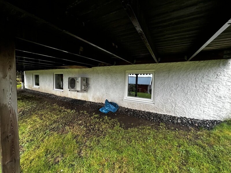 Nyinstallerade källarfönster med vita karmar i putsad husgrund