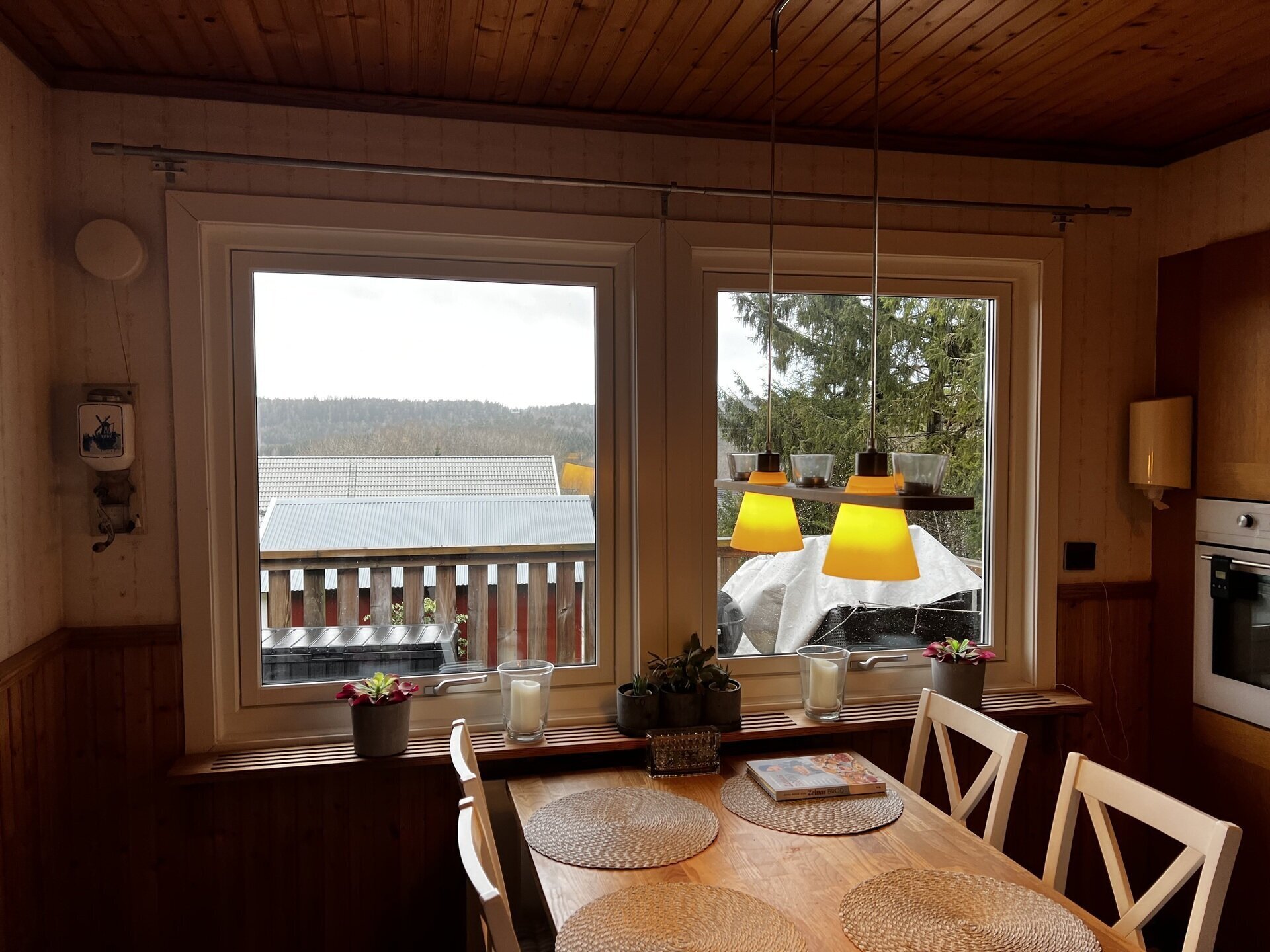 Nyinstallerade tvåluftsfönster med träkarm i kök med utsikt över balkong och sjö