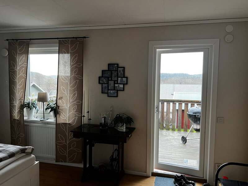 Nyinstallerad balkongdörr med fönster och utsikt mot balkong och sjö i sovrum