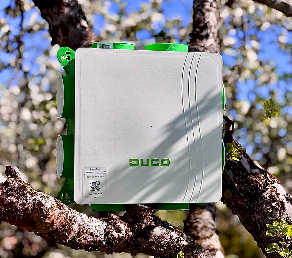 Duco ventilationsaggregat i vitt och grönt, fotomontage bland trädgrenar