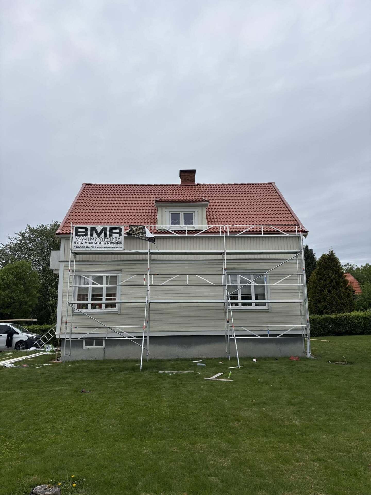 Ljust trähus med ställning längs fasaden och rött tegeltak, BMR Värmlands skylt på ställningen