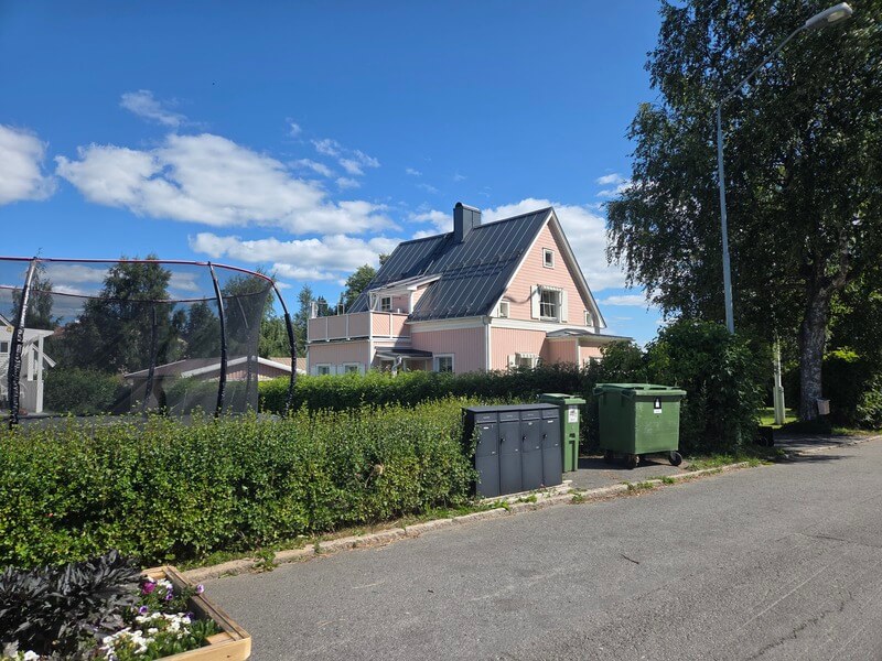 Rosa villa med nytt mörkt plåttak i sommarmiljö
