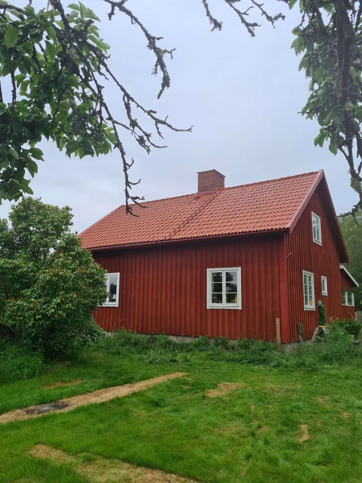 Röd villa med nylagt rött tegelpannetak och tegelskorsten