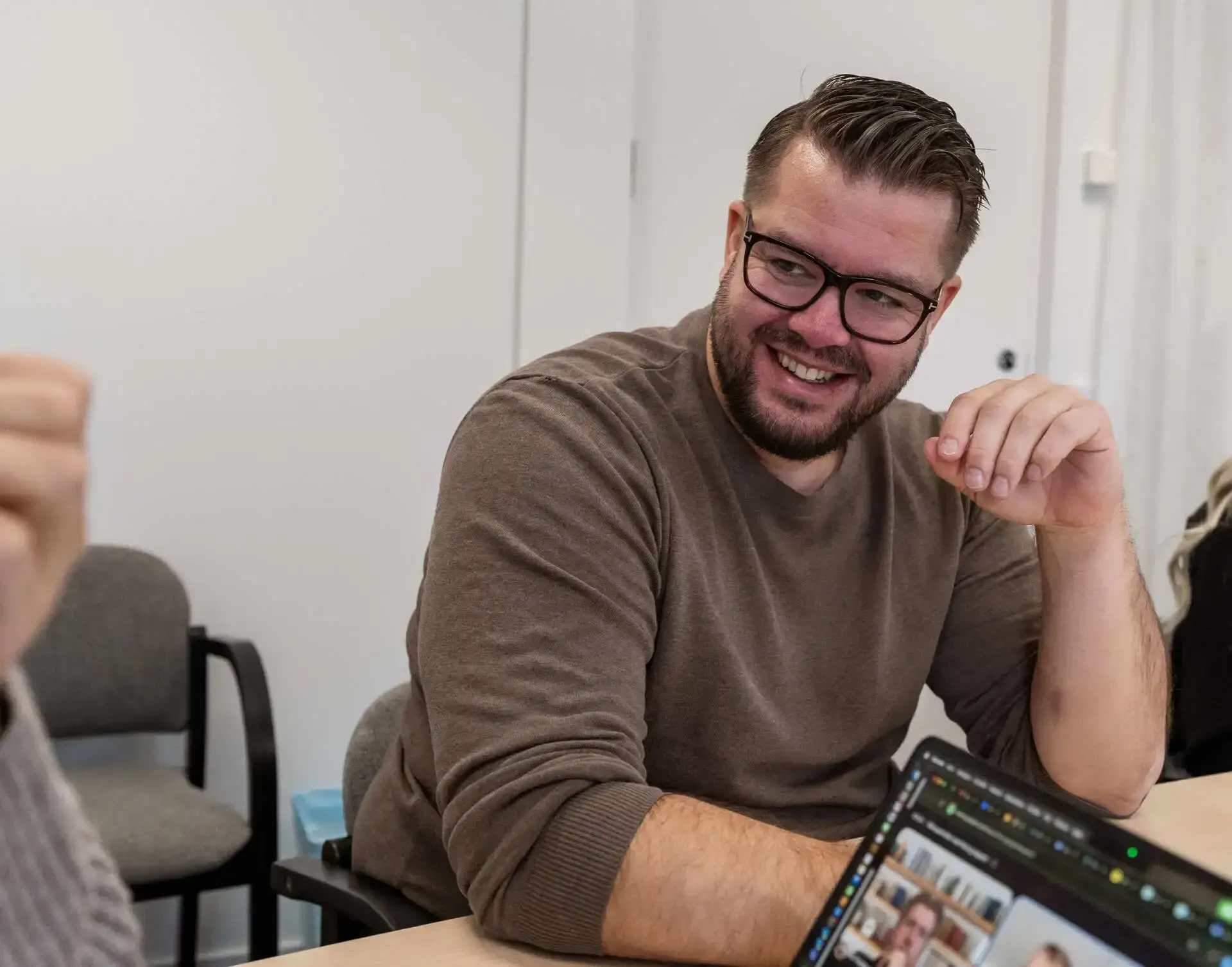 Skrattande medarbetare med glasögon vid en laptop under ett möte