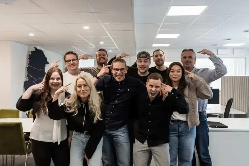 Delar av teamet samlade i det nya kontorslandskapet, alla pekar skrattande mot mitten