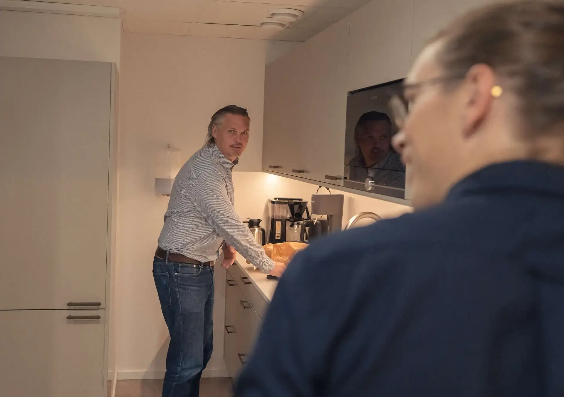 Två kollegor i köket på nya kontoret, en står vid kaffemaskinen