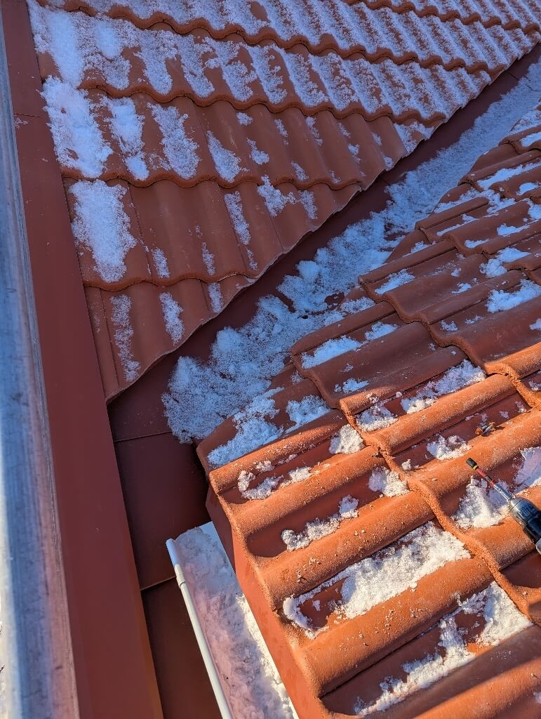 Röda tegelpannor, snötäckt tak – Örjansgatan i Borlänge, takbyte av Sol och Tak Dalarna