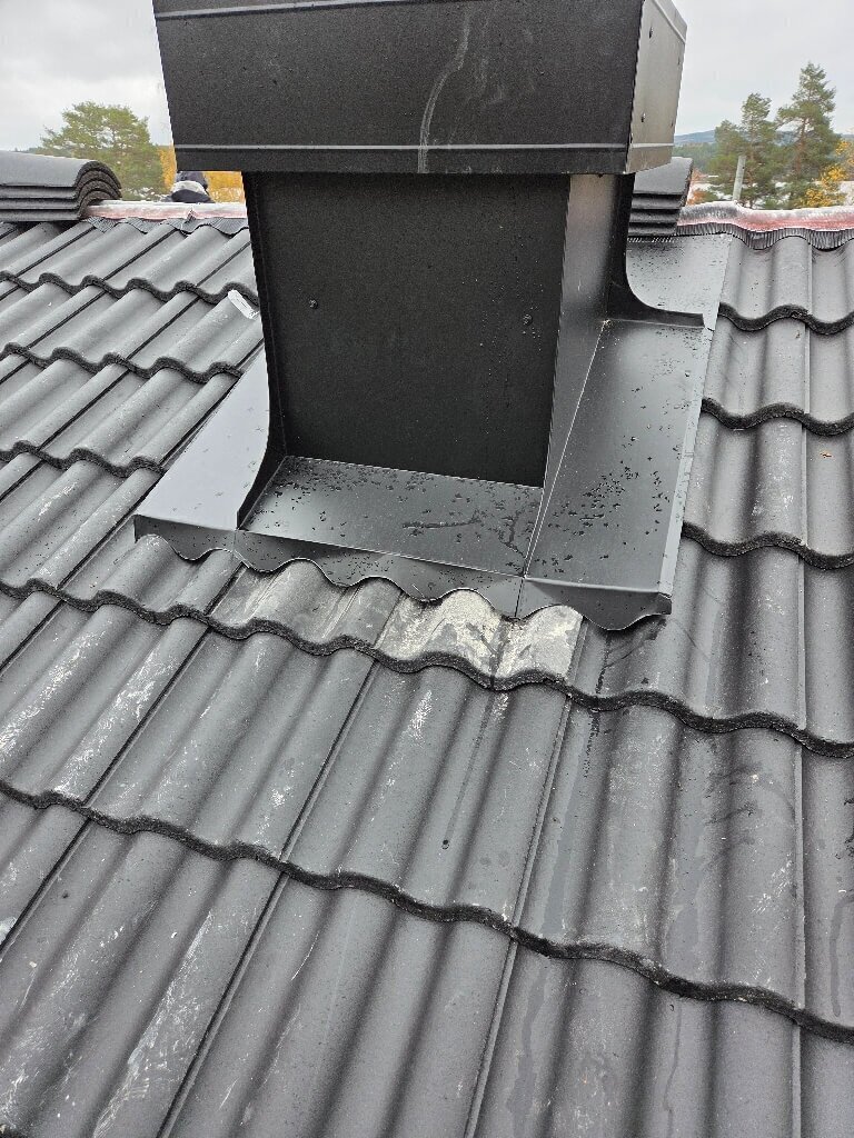 Färdigt tak med svarta betongpannor och plåtklädd skorsten i Övre Sundsnäs, Leksand