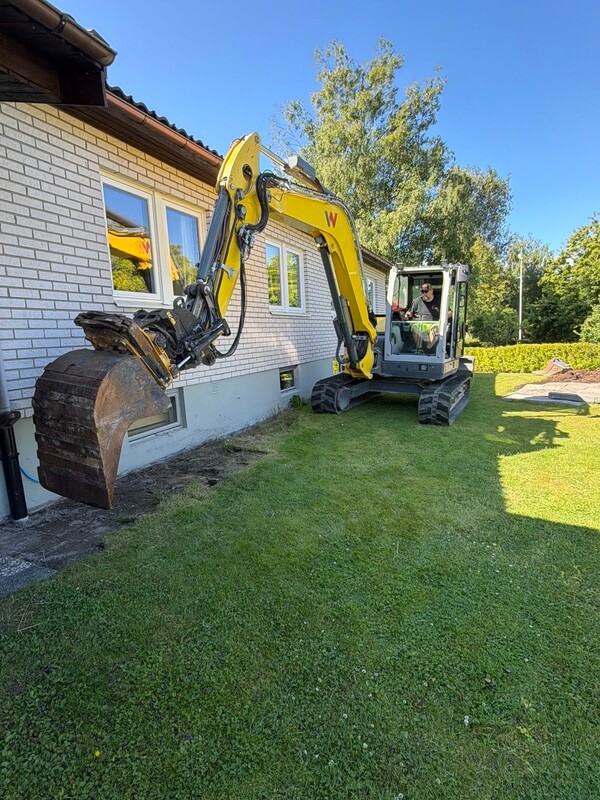 Grävmaskin schaktar längs villans grund vid dränering i Karlskoga
