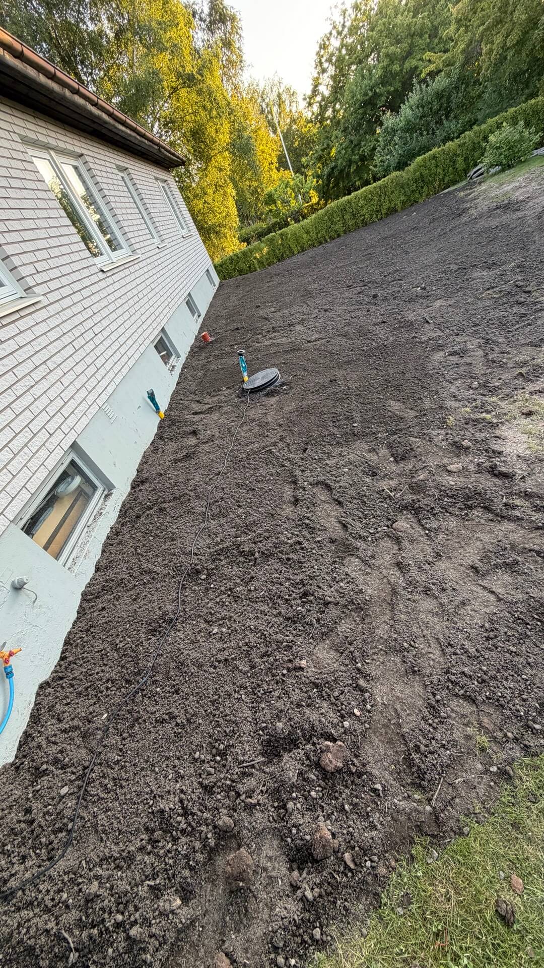 Återfylld och planerad mark längs husgrund efter dränering i Karlskoga