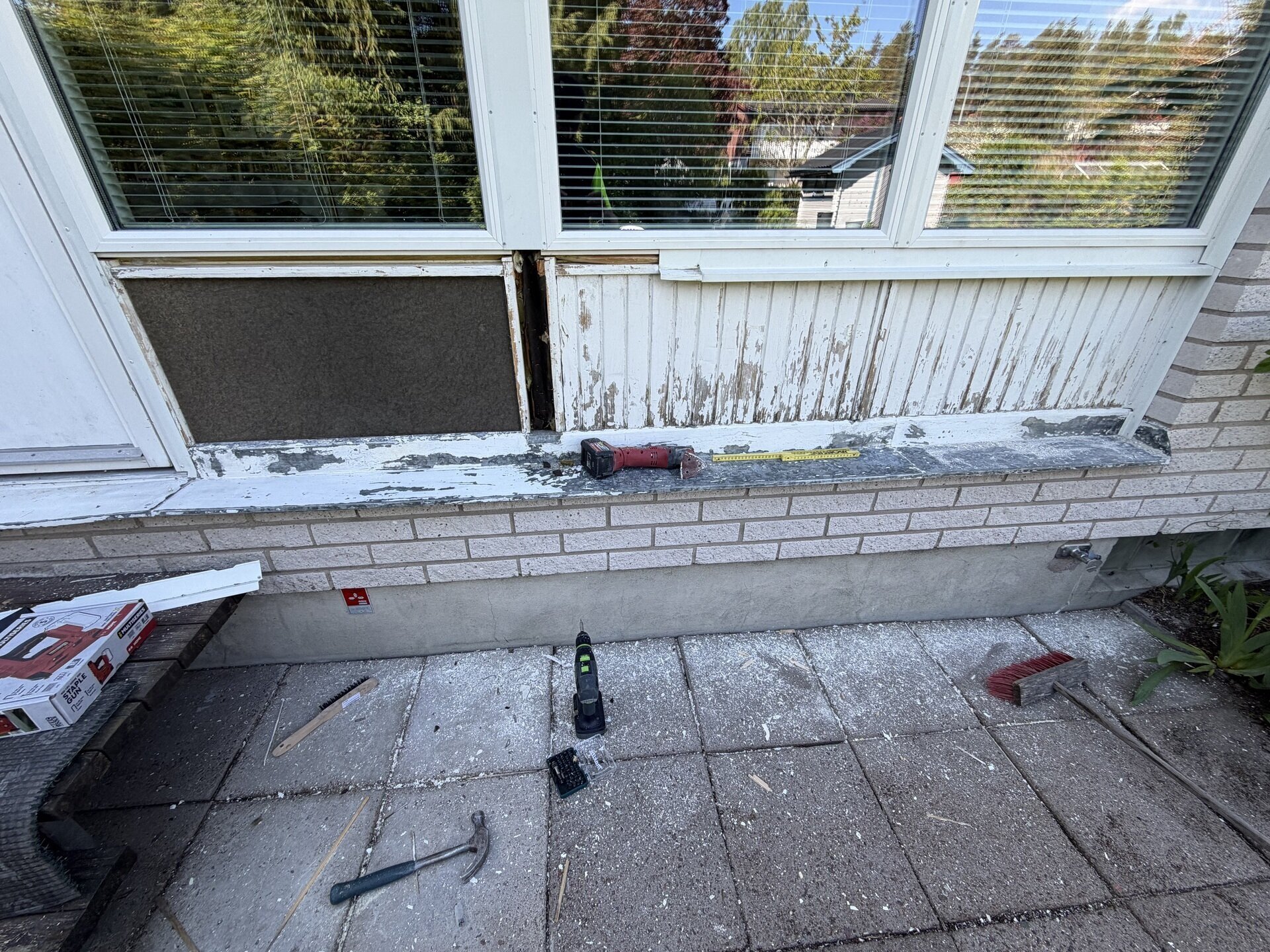 Skadad fasadpanel under fönster före fasadrenovering i Stockfallet