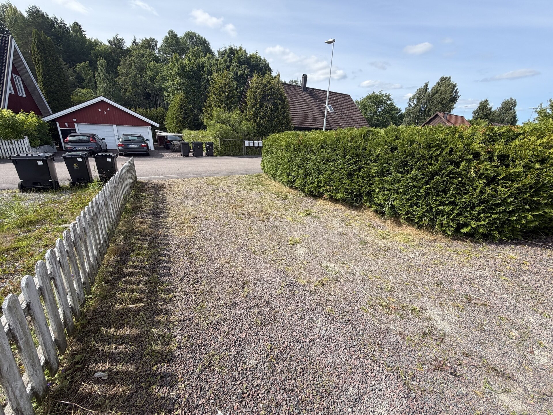 Grusuppfart med klippt häck och staket efter trädgårdsskötsel i Vålberg
