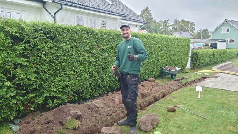 Medarbetare från DACI Solutions vid ett nygrävt dike längs en häck i en villaträdgård