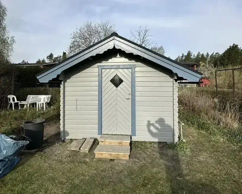 Nymålad förrådsbod i ljusgrått med vita detaljer