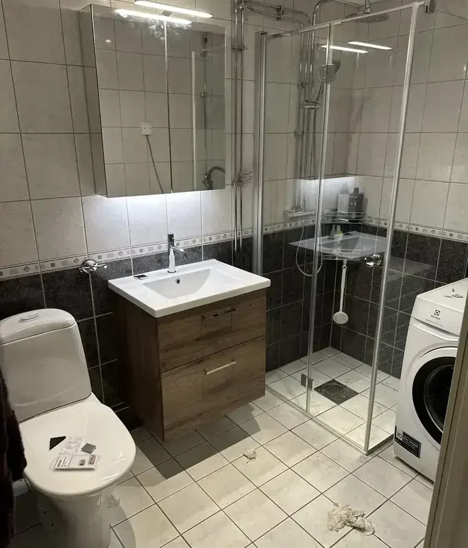 Badrum med dusch, kommod och nya ytskikt efter montering och renovering
