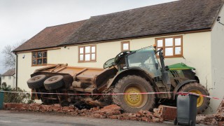 Tractor towing a trailer crashes through the front of a house