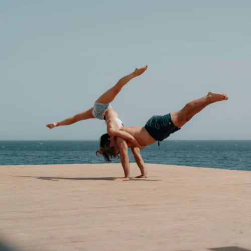 male and female performing advanced yoga pose on a beautiful beach