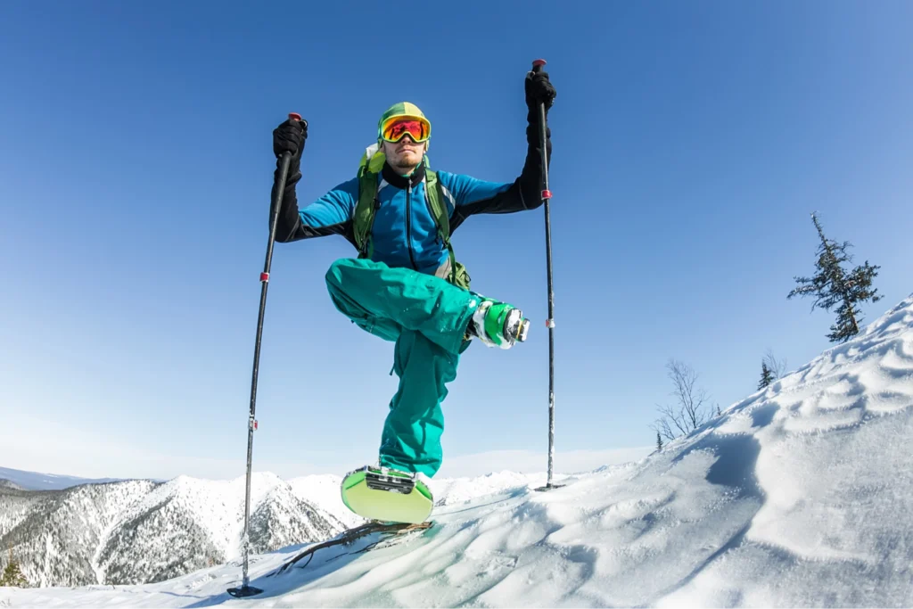 Skier balancing on one leg on top of a mountain.