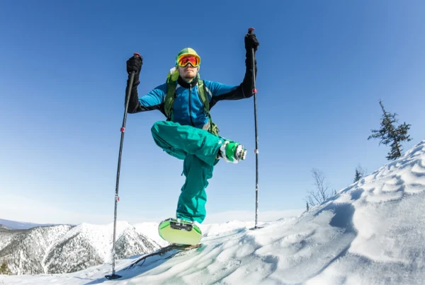 Skier balancing on one leg on top of a mountain.