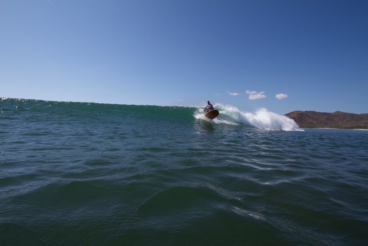 Harris surfing his otter wooden paddleboard
