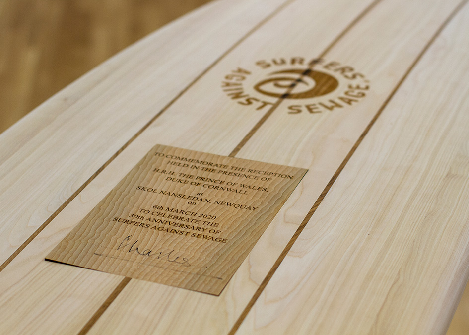 prince of wales prince charles duke of cornwall signs wooden surfboard to signify patronage for surfers against sewage hugo tagholm James Otter making surfboard in workshop