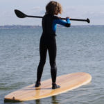 Otter surfboards wooden stand up paddle board on the water with boy