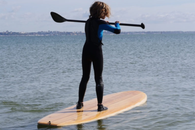 Otter surfboards wooden stand up paddle board on the water with boy