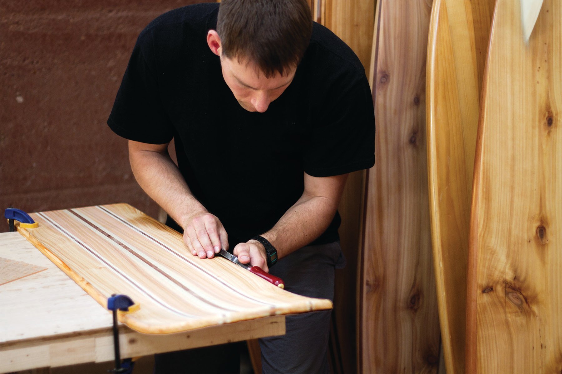 Rasping the rails of an otter surfboards wooden bellyboard workshop course Tony