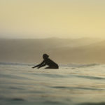 Becky knee paddles a wooden longboard at Perranporth Cornwall. Otter Surfboard summer hand made seasaw