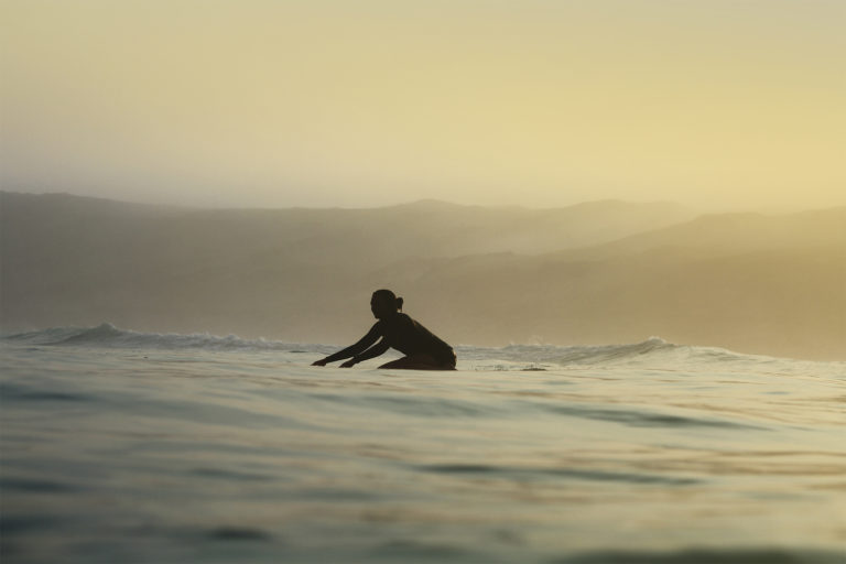 Becky knee paddles a wooden longboard at Perranporth Cornwall. Otter Surfboard summer hand made seasaw