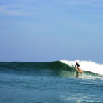 James Otter drops into a wave on the Pier wooden surfboard at Chapel Porth, Cornwall in summer. Riz Boardshorts