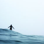 Becky gliding along a wave in the mist on the Otter Surfboards wooden Seasaw model